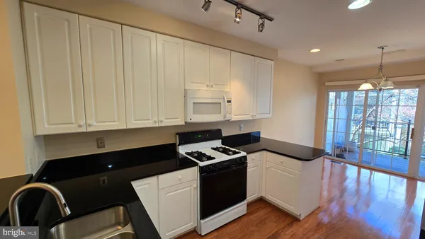 a kitchen with granite countertop white cabinets and black appliances