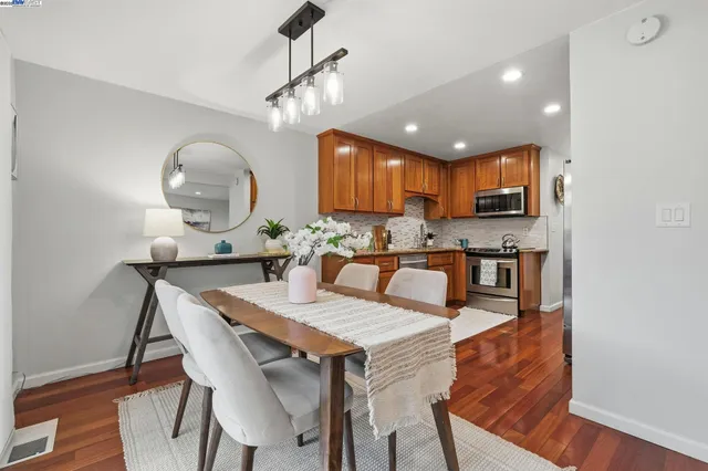 a kitchen with a dining table chairs and wooden floor