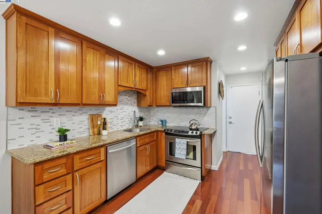 a kitchen with stainless steel appliances granite countertop wooden cabinets a stove top oven a sink and dishwasher
