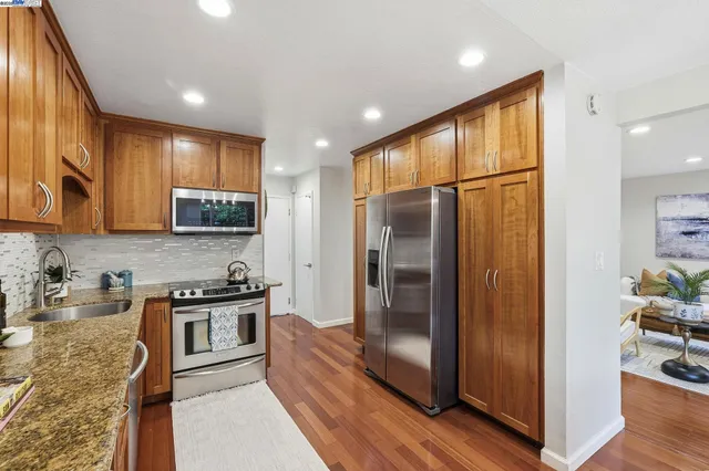 a kitchen with stainless steel appliances granite countertop a refrigerator a stove a sink and a cabinets