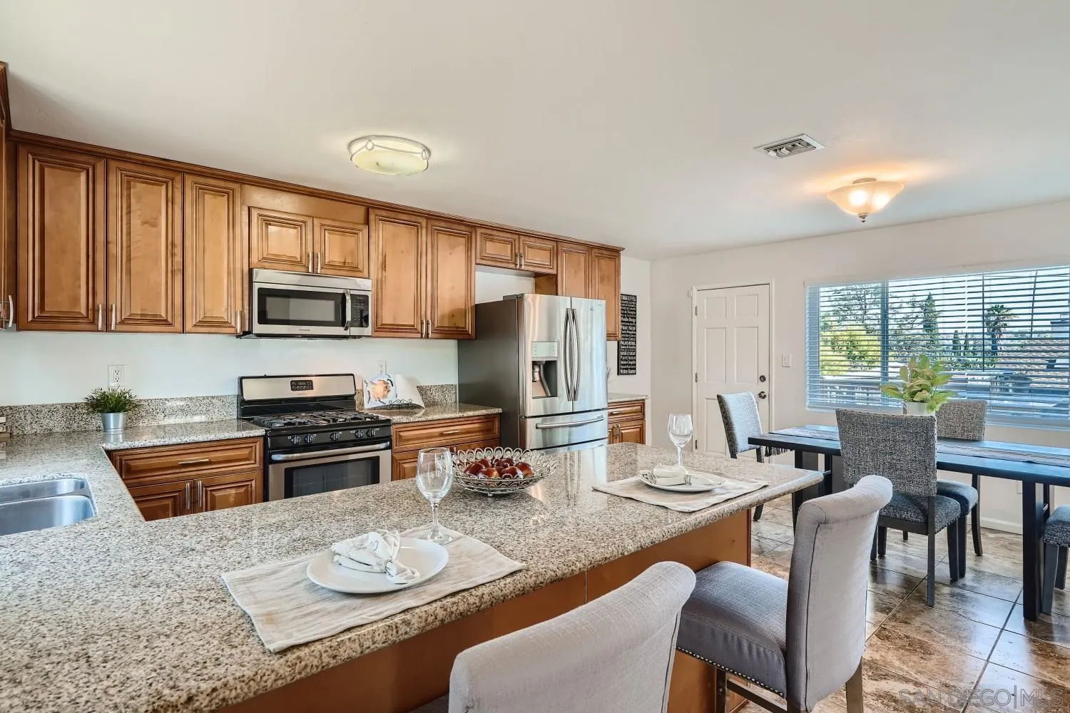 4817 Maple Avenue La Mesa, CA 91942 - Photo 15 of 31 a kitchen with stainless steel appliances granite countertop a stove top oven a sink a stove a dining table and chairs with wooden floor