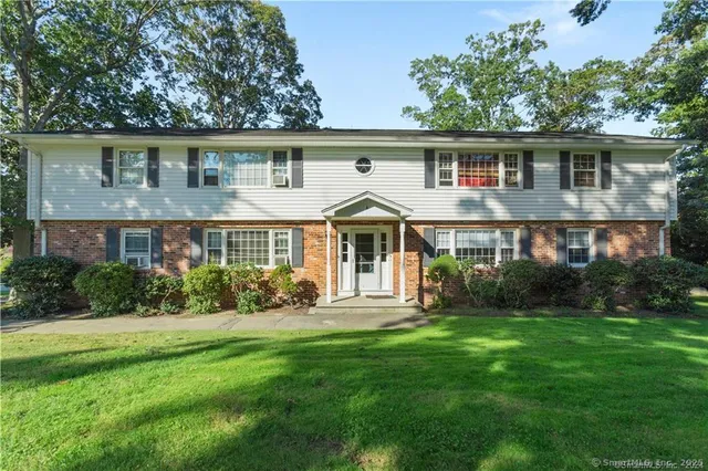 a front view of a house with a yard and green space