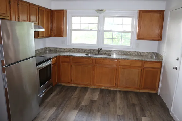 a kitchen with granite countertop stainless steel appliances a counter space and a window