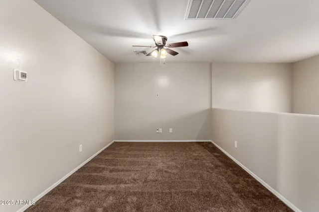 an empty room with a window and ceiling fan