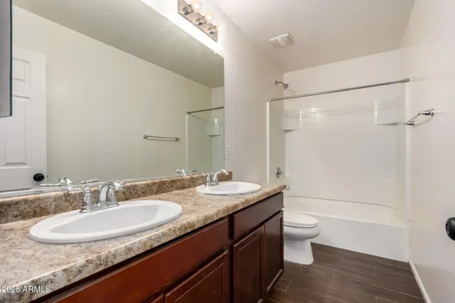 a bathroom with a granite countertop sink a toilet a mirror and shower