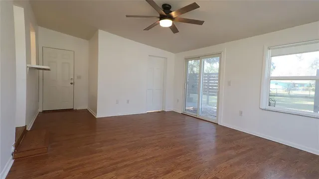 a view of an empty room with a window and wooden floor