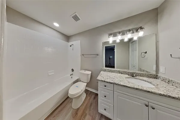 a bathroom with a granite countertop sink a toilet and bathtub