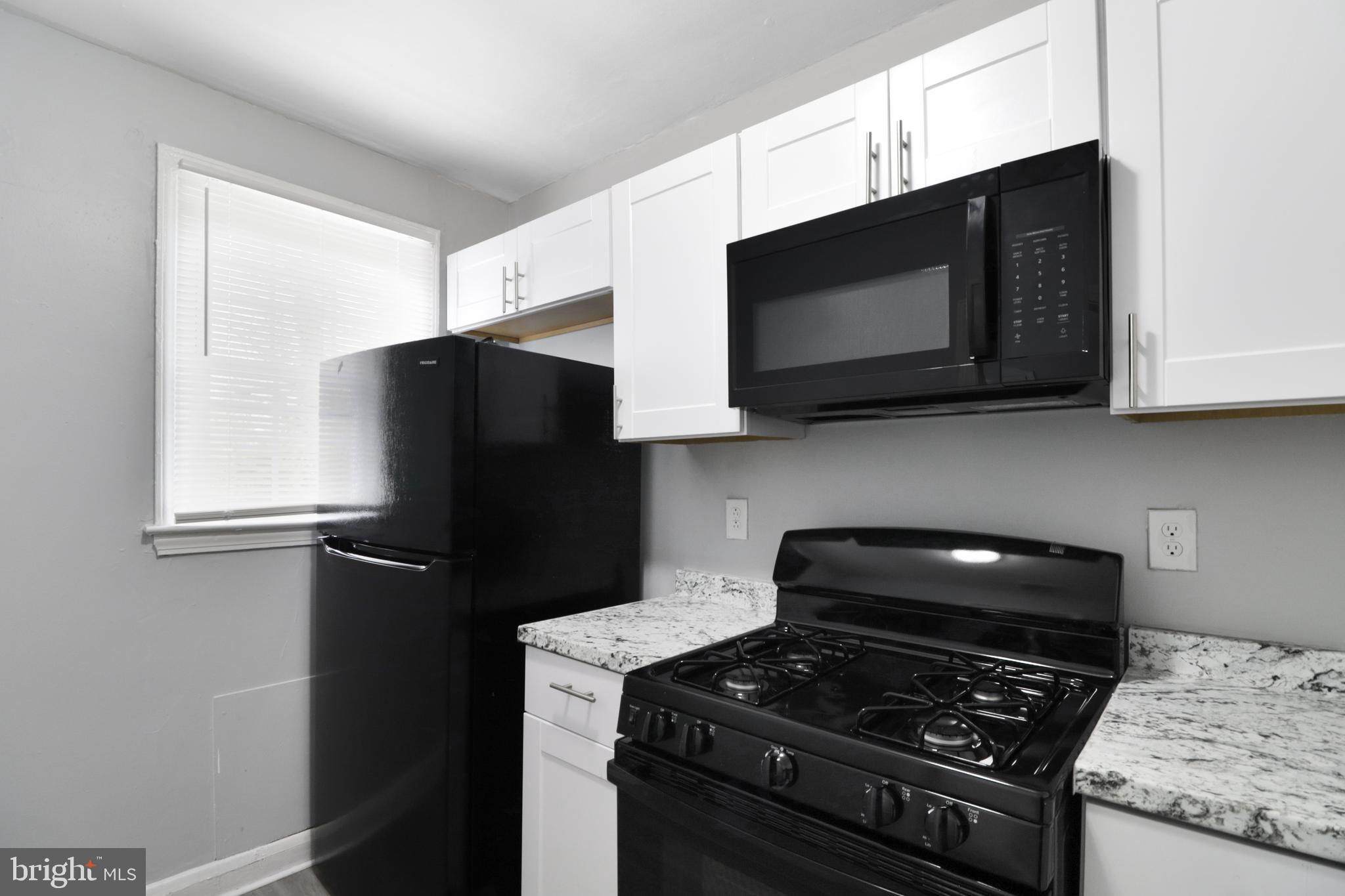 6151 Chinquapin Parkway Baltimore, MD 21239 - Photo 19 of 22 a kitchen with stainless steel appliances granite countertop white cabinets and black stove top oven with granite countertops