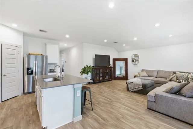 a living room with furniture a wooden floor and kitchen view