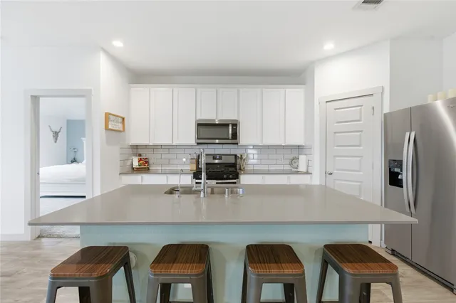 a kitchen with stainless steel appliances granite countertop a table chairs refrigerator and sink