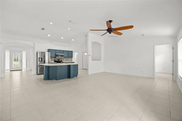 a view of kitchen with kitchen island stainless steel appliances a stove a sink a refrigerator white cabinets and wooden floor