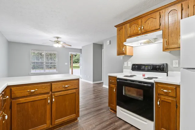 an empty room with wooden floor chandelier fan and windows