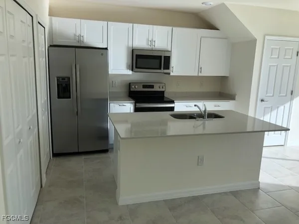 a kitchen with granite countertop a refrigerator and a stove top oven
