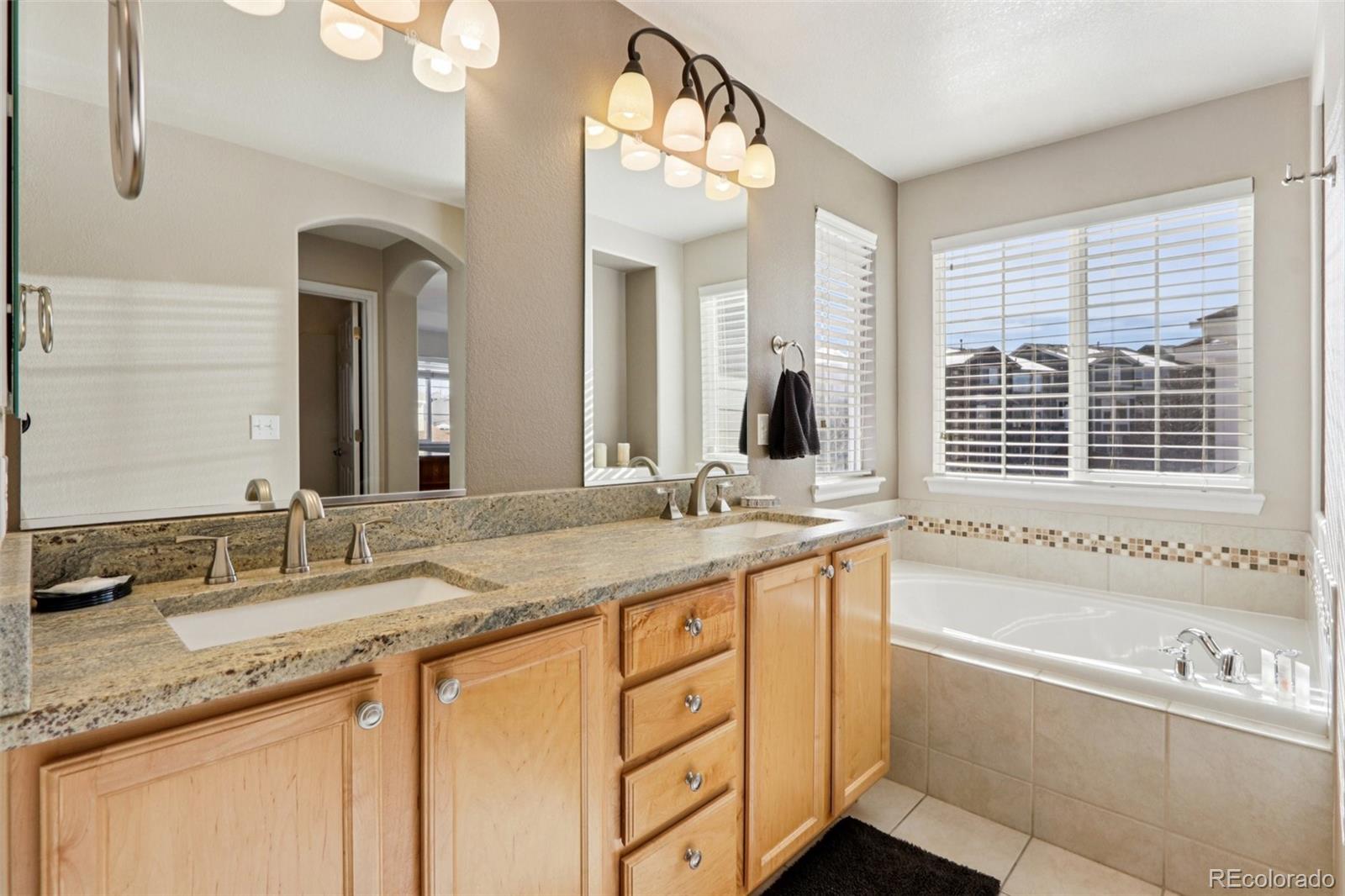 3120 Redhaven Way Highlands Ranch, CO 80126 - Photo 32 of 50 a bathroom with a granite countertop sink mirror and a bathtub next to a window