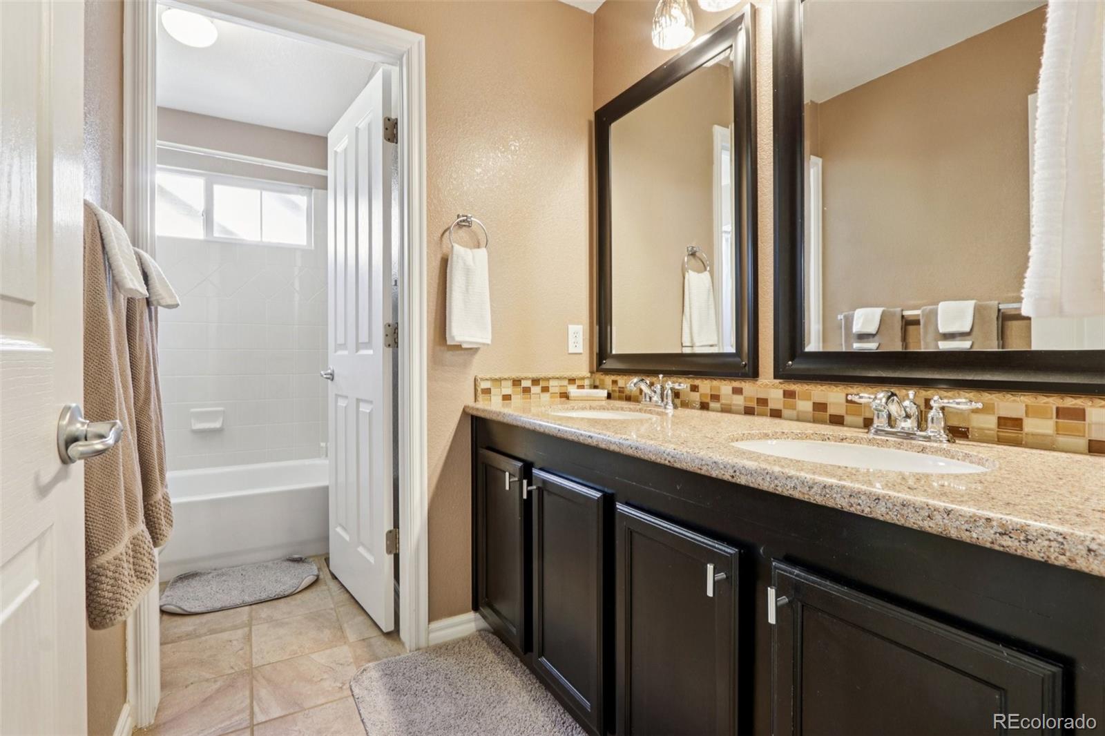 3120 Redhaven Way Highlands Ranch, CO 80126 - Photo 42 of 50 a bathroom with a granite countertop sink mirror and a bathtub