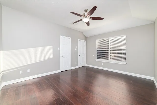an empty room with wooden floor and windows