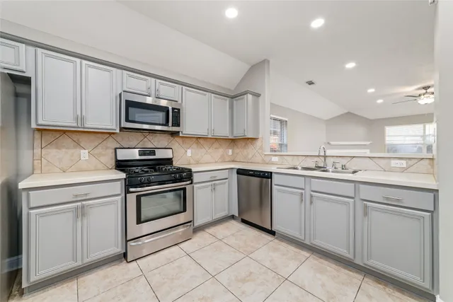 a kitchen with granite countertop white cabinets sink and stainless steel appliances