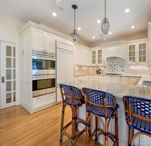 a kitchen with stainless steel appliances granite countertop a kitchen island a stove a dining table and chairs with wooden floor