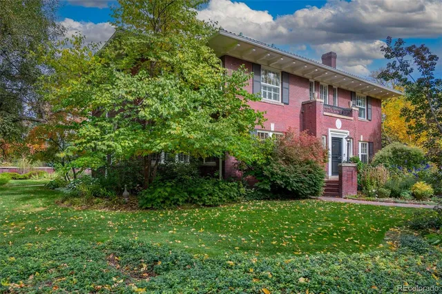 a view of a brick house with a yard and plants