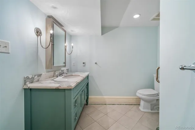 a bathroom with a granite countertop sink a toilet and a mirror