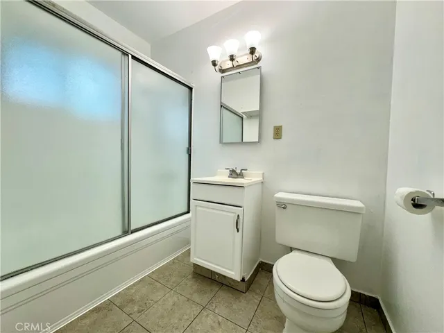 a bathroom with a granite countertop toilet sink and mirror