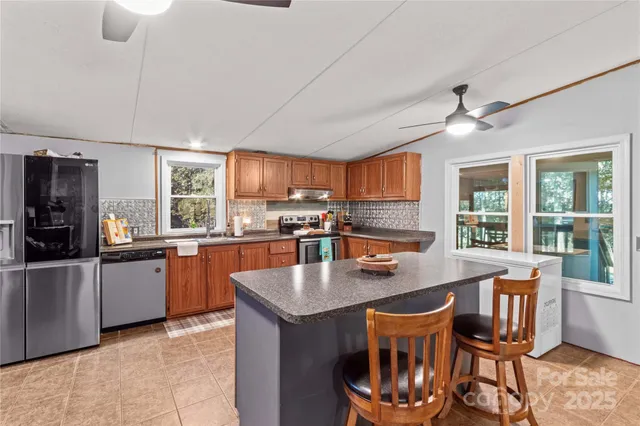 a kitchen with stainless steel appliances granite countertop a stove a refrigerator a kitchen island a dining table and chairs with wooden floor