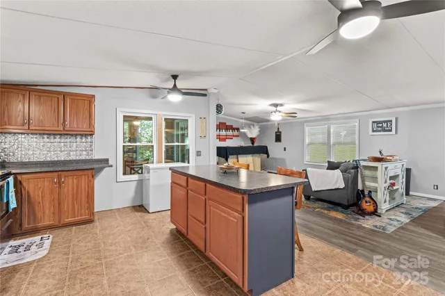 a kitchen with kitchen island granite countertop a stove top oven a chimney cabinets and living room view