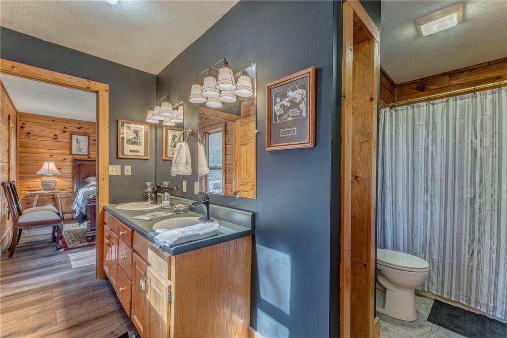 4569 Old Dalton Road Northeast Rome, GA 30165 - Photo 40 of 53 a bathroom with a granite countertop sink a toilet a mirror and shower curtain
