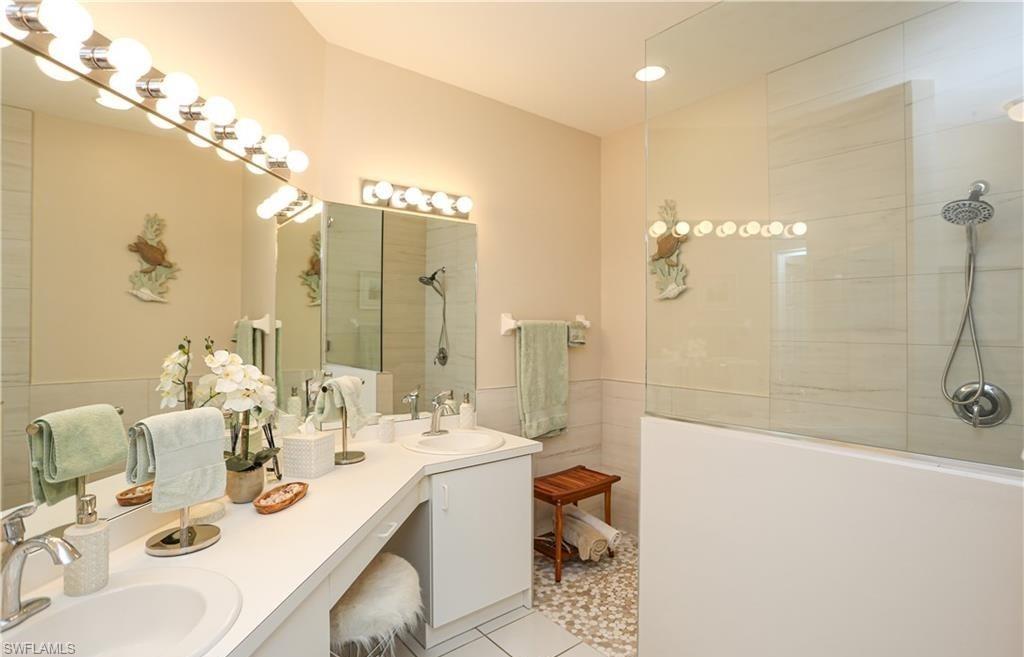 3775 Fieldstone Boulevard, Unit 102 Naples, FL 34109 - Photo 15 of 27 a bathroom with a double vanity sink mirror and shower