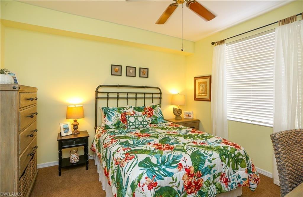3775 Fieldstone Boulevard, Unit 102 Naples, FL 34109 - Photo 17 of 27 a bedroom with a bed and a chandelier