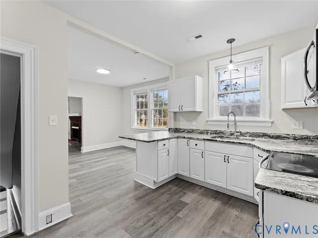 a kitchen with granite countertop white cabinets and a wooden floor