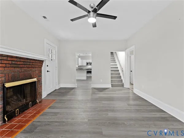 a view of an empty room with wooden floor fireplace and a window