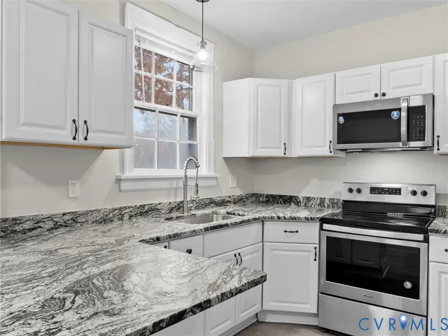 a kitchen with granite countertop a stove top oven microwave and cabinets