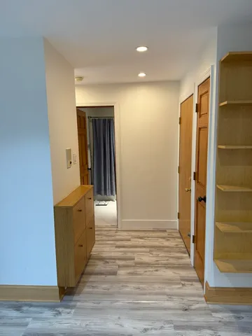 a view of an empty room with glass door and wooden floor