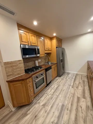 a kitchen with stainless steel appliances granite countertop a refrigerator and a stove top oven