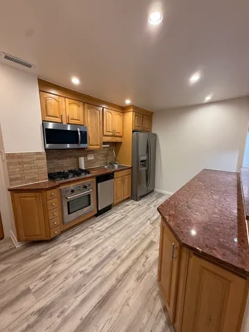 a kitchen with stainless steel appliances kitchen island granite countertop a stove a sink and a refrigerator