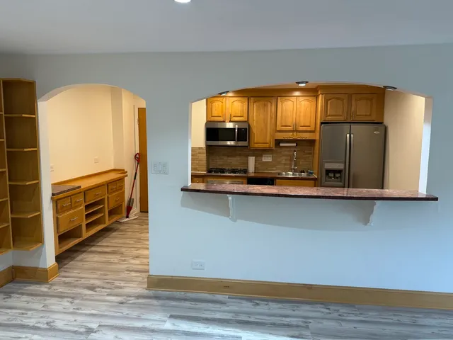 a living room with stainless steel appliances wooden floor and a large window