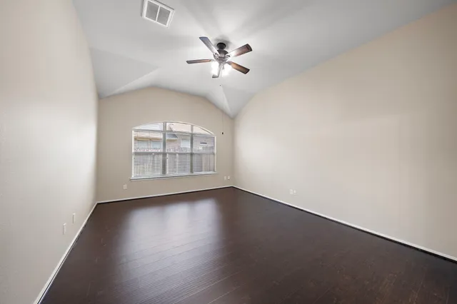 an empty room with wooden floor chandelier fan and windows