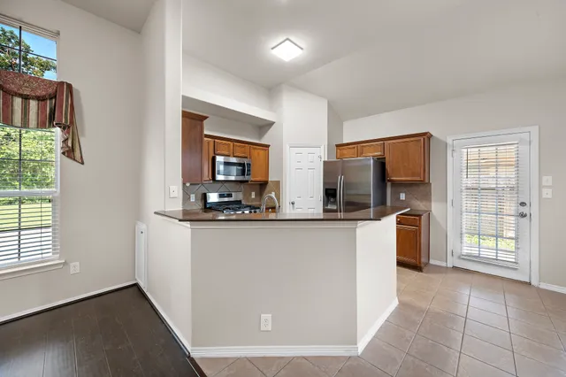 a living room with stainless steel appliances granite countertop furniture a flat screen tv and a window
