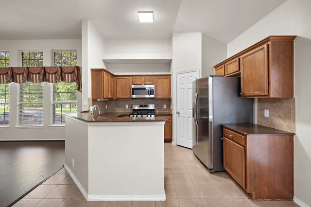 a kitchen with stainless steel appliances granite countertop a refrigerator a stove and a sink