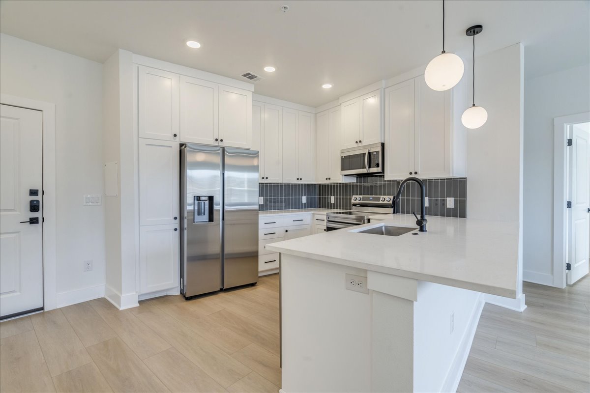 3000 Duval Street, Unit 203 Austin, TX 78705 - Photo 3 of 27 a kitchen with stainless steel appliances granite countertop a stove a refrigerator a sink a microwave a counter top and oven with wooden floor