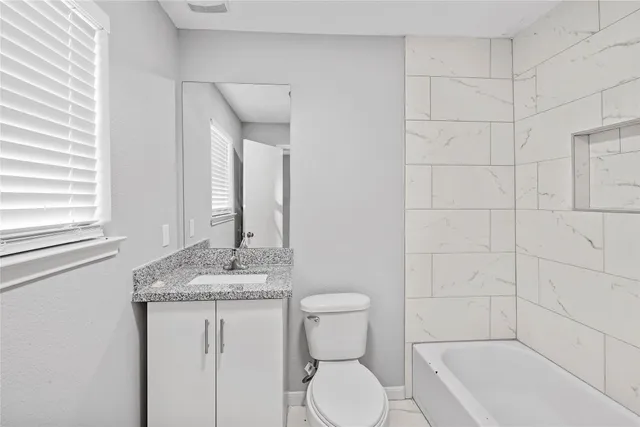 a bathroom with a granite countertop sink toilet and shower
