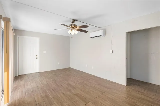 an empty room with wooden floor fan and windows