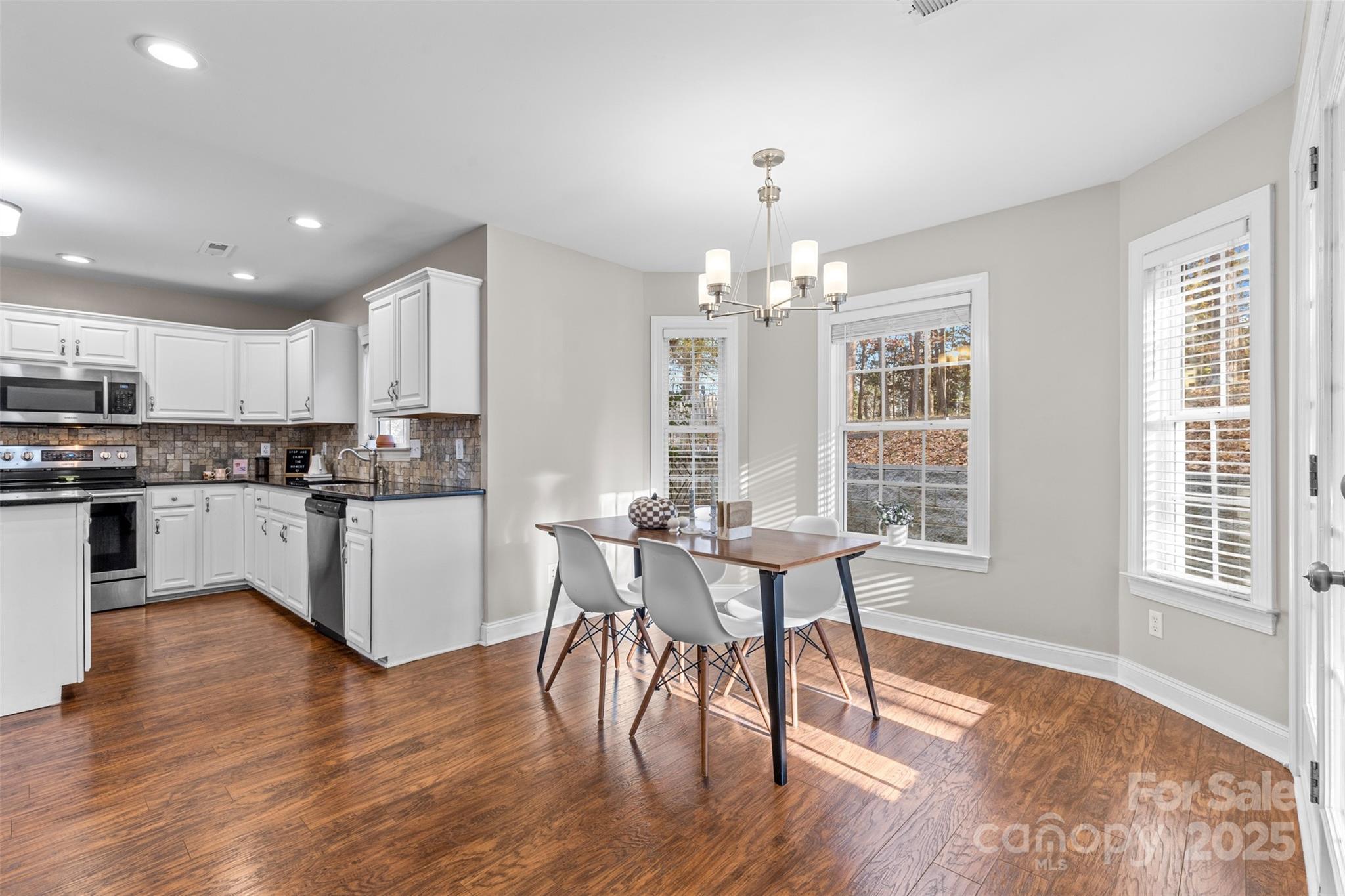 1108 Blowing Rock Cove Fort Mill, SC 29708 - Photo 9 of 43 a kitchen with stainless steel appliances granite countertop a stove top oven a sink dishwasher a dining table and chairs with wooden floor