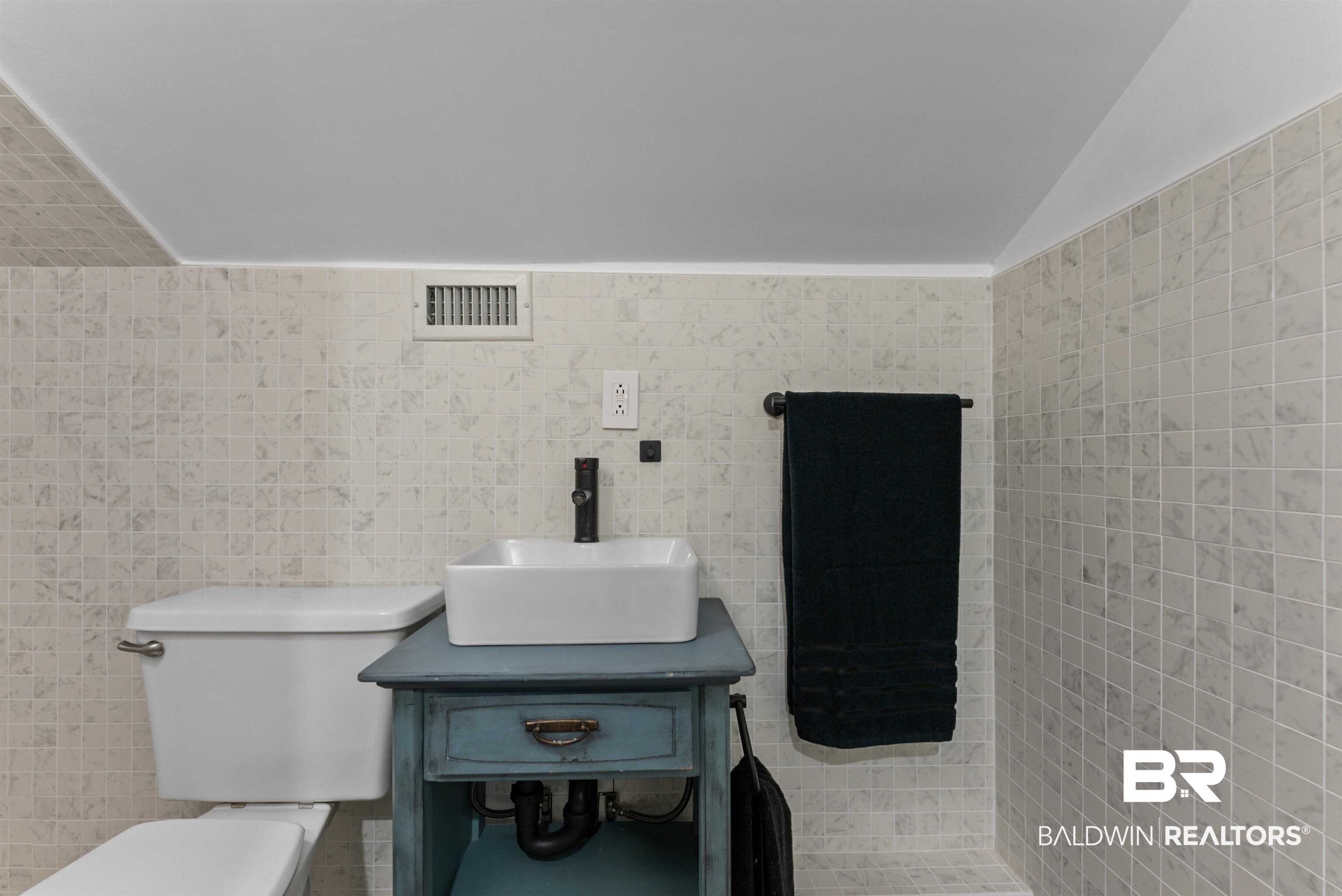 6447 Bemis Lane Bon Secour, AL 36511 - Photo 45 of 62 Bathroom featuring full-height mosaic tile walls, a white vessel sink, and a black wall-mounted faucet