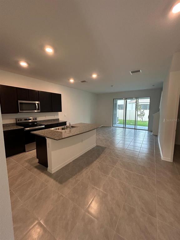 16620 Grotto Steam Place Wimauma, FL 33598 - Photo 5 of 19 a kitchen with stainless steel appliances a refrigerator and a stove top oven