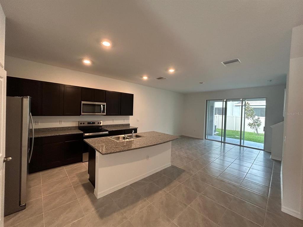 16620 Grotto Steam Place Wimauma, FL 33598 - Photo 7 of 19 a kitchen with stainless steel appliances a stove a sink and a refrigerator