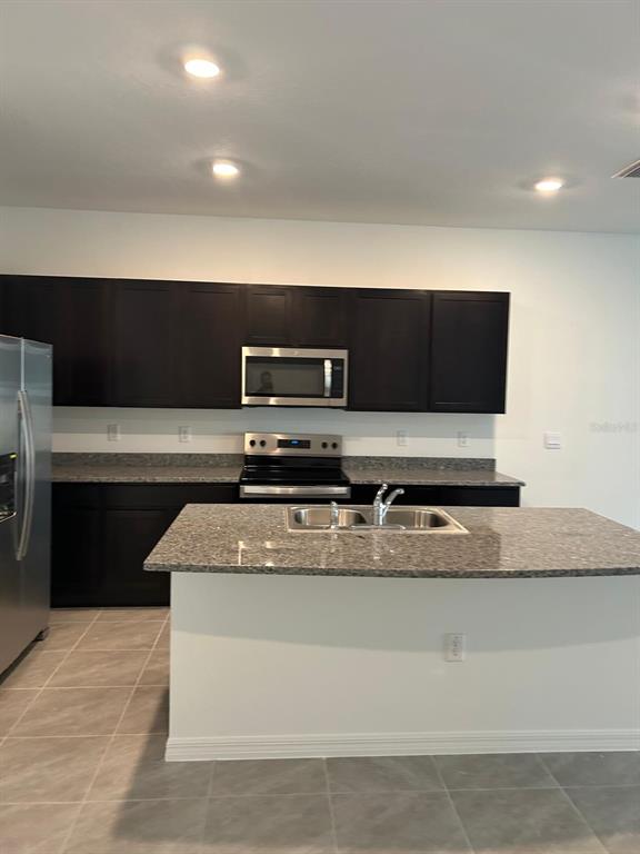 16620 Grotto Steam Place Wimauma, FL 33598 - Photo 8 of 19 a kitchen with stainless steel appliances granite countertop a sink and a stove