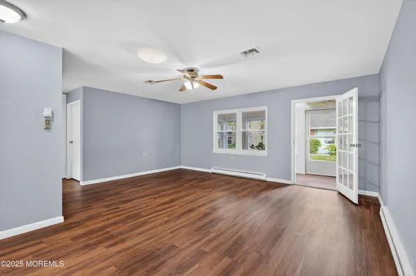 a view of an empty room with a window and wooden floor