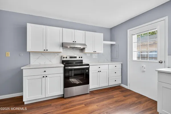 a kitchen with granite countertop white cabinets and stainless steel appliances